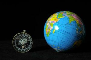 ein Globus und ein Kompass auf ein schwarz Hintergrund foto