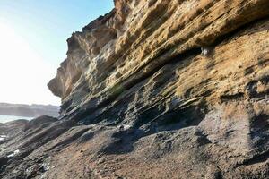 das Sonne scheint auf ein felsig Cliff in der Nähe von das Ozean foto