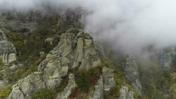 oben Aussicht auf Linderung von Felsen Herbst im Nebel. Schuss. Aussicht von Felsen Formationen von Berg mit farbig trocken Gras und Sträucher auf Nebel Hintergrund foto