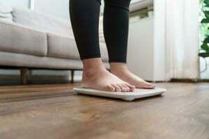 Fett Diät und Rahmen Füße Stehen auf elektronisch Waage zum Gewicht Kontrolle. Messung Instrument im Kilogramm zum ein Diät Kontrolle. foto