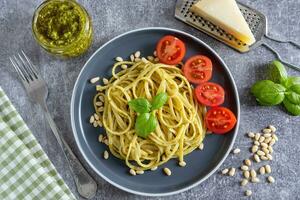 traditionell Italienisch Spaghetti Pasta mit Pesto Soße und frisch Basilikum Blätter im schwarz Schüssel foto