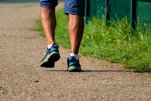 Mann Gehen mit Turnschuhe auf ein Weg, Nahansicht von seine Beine, Sport Aktivität, gesund Lebensstil foto