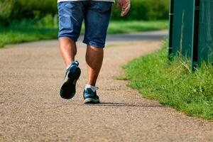 Mann Gehen mit Turnschuhe auf ein Weg, Nahansicht von seine Beine, Sport Aktivität, gesund Lebensstil foto