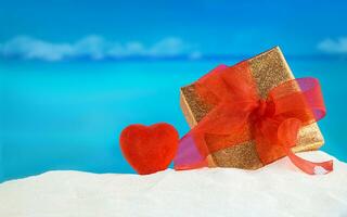 golden Geschenk Box mit rot Bogen und Herz auf sandig Strand, mit Meer hinter. Urlaube, Entspannung, Reise zu heiß Länder. st. Valentinstag, Mutter und Damen Tag foto