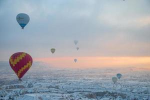 Heißluftballons fliegen über spektakuläres Kappadokien. Schöne Aussicht auf Heißluftballons, die im hellen Himmel des Sonnenaufgangs über der Berglandschaft von Göreme schweben foto