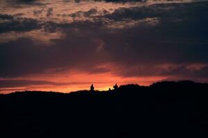 Menschen Stehen auf oben von das Dünen beim Sonnenuntergang foto