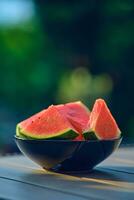 Wassermelone Scheiben im schwarz Schüssel auf Tabelle foto