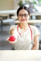 medizinisch Schüler Aktion geben ein Gummi rot Herz auf verschwommen Hintergrund. asiatisch medizinisch Schüler mit Herz Krankheit Konzept. foto