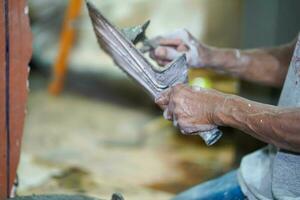 Nahansicht Hände von Baumeister halten Granatwerfer schwenken zum Verputzen Wände mit Zement im Konstruktion Seite? ˅ foto