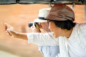 Nahansicht amerikanisch Senior Tourist Mann nehmen ein Stadt Tour Tuk Tuk Thailand Taxi und nehmen ein Foto mit seine Tour leiten zeigen aus das interessant setzt im das Stadt. Senior Tourist Konzept