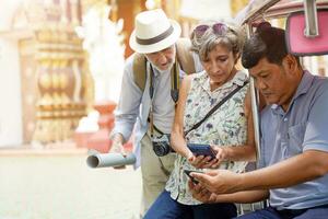 europäisch Senior Tourist Frau mit ihr Freund bezahlen das Fahrpreis zu das Tuk Tuk Thailand Taxi Treiber durch Clever Telefon auf verschwommen und Sonne hell Hintergrund. foto