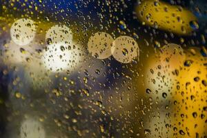 Regen Tropfen auf Fenster. friedlich Abend oder Nacht beim Zuhause wann regnet außen. Wasser Tropfen auf Glas. Oberfläche von nass Glas. Wasser Spritzen. Stadt Beleuchtung Bokeh während das Regen. foto