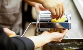 Koch macht Pasta mit einer Maschine, hausgemachte frische Pasta foto