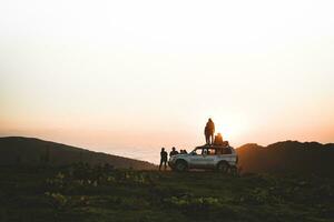 Gruppe von Reisende Tourist Stand durch 4wd Fahrzeug zusammen im Natur auf Abenteuer Uhr Sonnenuntergang Über Horizont Über Wolkenlandschaft im Wildnis. Erkundung und Abenteuer foto