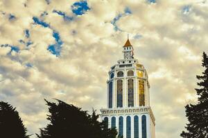 batumi, Georgia, 2021 - - Zeitraffer Sheraton Hotel Gebäude Turm die Architektur mit alt Uhr auf oben und Vorbeigehen Wolken Hintergrund. Ferien im batumi, Georgia foto