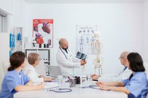 Arzt Arzt erklären Knochen Anatomie Struktur mit Körper Radiographie diskutieren Gesundheitswesen Behandlung. Krankenhaus Mannschaft Arbeiten im Konferenz Treffen Zimmer präsentieren medizinisch Sachverstand foto