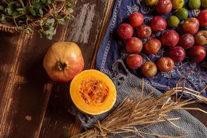 Kürbisse und viele andere Farben und Sorten von Obst und Gemüse stehen auf dem Holzmasertisch foto