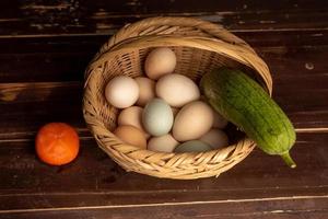 die Eier und anderes Obst und Gemüse im Korb liegen auf dem Holzmaserungstisch
