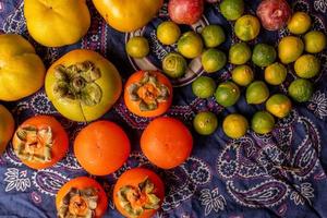 viele Farben und Obstsorten liegen entweder auf dem Teller oder verstreut auf dem Holztisch foto