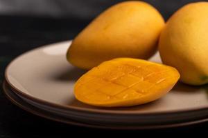 Schneiden und fertige Mangos auf einem Teller in einer dunklen Umgebung foto