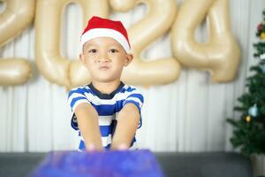 fröhlich Weihnachten 2024 Konzept ein Junge halten ein Geschenk Box ist glücklich zu erhalten ein Geschenk auf Weihnachten Tag. foto