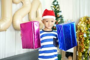 fröhlich Weihnachten 2024 Konzept ein Junge halten ein Geschenk Box ist glücklich zu erhalten ein Geschenk auf Weihnachten Tag. foto