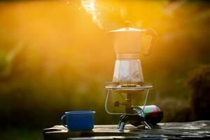 Moka Topf und Rauch, Dampf von das Kaffee Topf auf Feuer, im das Wald beim Sonnenaufgang im das Morgen. Sanft Fokus. flach Fokus Wirkung. foto