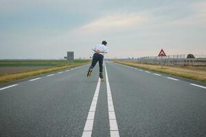 gut aussehend jung Athlet Rollerblades auf Niederländisch Straßen zu verbessern Ausdauer und Fitness. ein jung Mann Züge Stabilität und genießen das frisch Luft. Sport Lebensstil foto