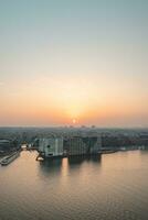 Hauptstadt von das Niederlande, Amsterdam unter das zuletzt Strahlen von Tag. das Stadt Center und Eisenbahn Bahnhof während Sonnenuntergang foto