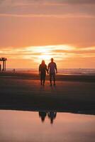 romantisch gehen von ein jung Paar auf das Strände von Ostende im Western Belgien beim Sonnenuntergang. Liebe und Hingabe. Betrachtung im ein Schwimmbad von Wasser foto