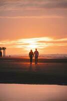 romantisch gehen von ein jung Paar auf das Strände von Ostende im Western Belgien beim Sonnenuntergang. Liebe und Hingabe. Betrachtung im ein Schwimmbad von Wasser foto