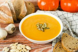 Kürbis Sahne Suppe und Roggen Brot auf ein hölzern Hintergrund. köstlich und gesund Lebensmittel. Nahansicht. foto