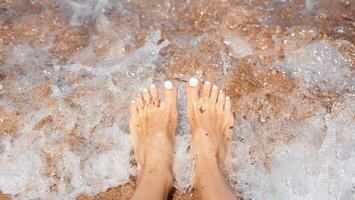 Frau Füße und Meer Welle. Ferien und Reise Konzept. Nahansicht. foto