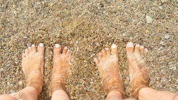 des Mannes und Frau Füße im das Wasser im das Meer. Ferien durch das Meer und Entspannung auf das Strand. Nahansicht. foto