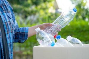 asiatische freiwillige frau tragen wasserplastikflaschen in müllkiste im park, recyceln abfallumgebungsökologiekonzept foto