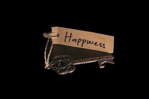 alt dekorativ Schlüssel und handgeschrieben Etikett Glück gebunden mit Stroh Seil auf schwarz Hintergrund foto