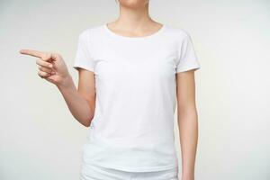 Innen- Schuss von jung weiblich im Basic Weiß T-Shirt zeigen beiseite mit Zeigefinger während zeigen Brief G auf Zeichen Sprache, Stehen Über Weiß Hintergrund foto
