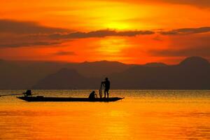 Silhouetten von Fischer beim das See mit Sonnenuntergang, Thailand. foto