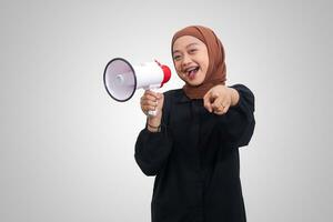 Porträt attraktiv von asiatisch Hijab Frau im beiläufig Hemd Sprechen lauter mit Megaphon, fördern Produkt. Werbung Konzept. isoliert Bild auf Weiß Hintergrund foto
