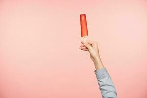 Innen- Foto von angehoben jung weiblich Hand behalten Eis mit Finger während posieren Über Rosa Hintergrund. Essen und Süßigkeiten Schüsse Konzept