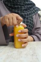 Frauen halten ein Flasche von Orange Saft versuchen zu entfernen das Flasche Deckel foto