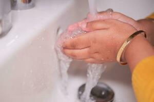 Kind wäscht sich die Hände mit Seife foto
