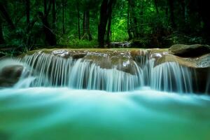 Bewegung Blau Wasser von klein Wasserfall im das dunkel Wald. foto