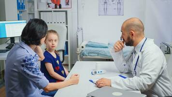 Sitzung beim Schreibtisch und Schreiben Behandlung zum krank Kind. Gesundheitswesen Praktiker Arzt Spezialist im Medizin Bereitstellung Gesundheit Pflege Dienstleistungen radiographisch Behandlung Untersuchung im Krankenhaus Kabinett foto