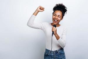 süßes Mädchen singt in ein Mikrofon, hat Spaß beim Singen auf weißem Hintergrund foto