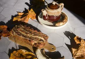 immer noch Leben Banane Kuchen mit ein Keramik Teekanne im das Strahlen von das Herbst Sonne foto