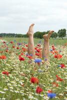 weiblich Beine Stock aus von das Feld von mehrfarbig Blumen, Explosion von Farbe foto