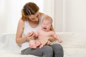 Mutter und Kind auf ein Weiß Bett. Mama und Baby Mädchen im Windel spielen im sonnig Schlafzimmer. foto