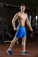 Mann Stehen stark im das Fitnessstudio und Biegen Muskeln foto