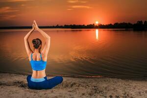 Yoga beim Sonnenuntergang auf das Strand. foto